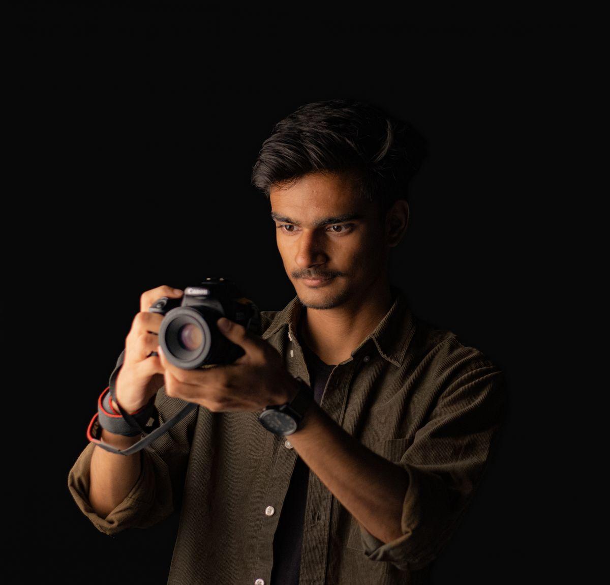 Photographer holding a camera against a dark background