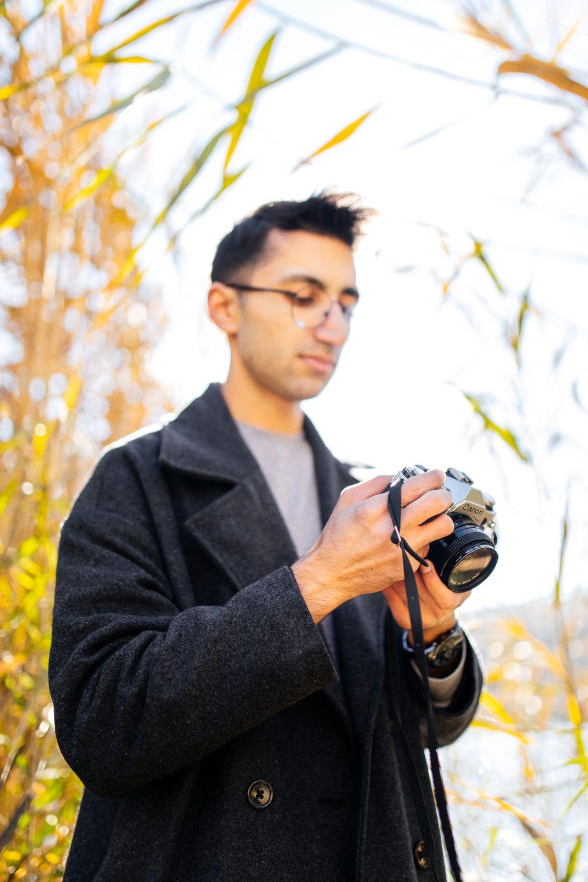 Photographer with a camera standing among reeds in autumn
